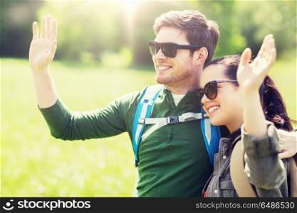 travel, hiking, backpacking, tourism and people concept - happy couple with backpacks waving hands outdoors. happy couple with backpacks hiking outdoors. happy couple with backpacks hiking outdoors