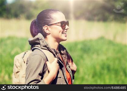 travel, hiking, backpacking, tourism and people concept - happy young woman in sunglasses with backpack walking outdoors. happy young woman with backpack hiking outdoors. happy young woman with backpack hiking outdoors