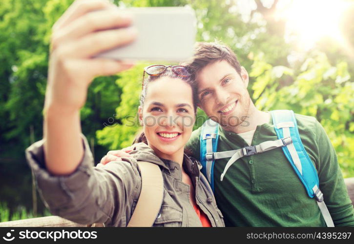 travel, hiking, backpacking, tourism and people concept - smiling couple with backpacks taking selfie by smartphone in nature. couple with backpacks taking selfie by smartphone. couple with backpacks taking selfie by smartphone