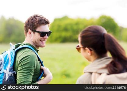 travel, hiking, backpacking, tourism and people concept - smiling couple with backpacks in nature looking at each other