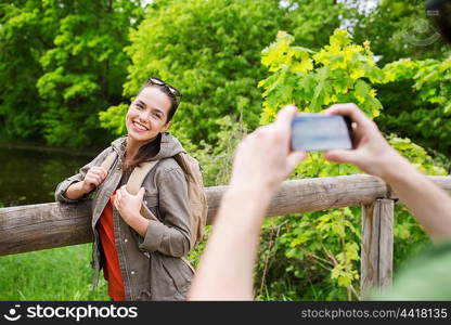 travel, hiking, backpacking, tourism and people concept - smiling couple with backpacks taking picture by smartphone in nature