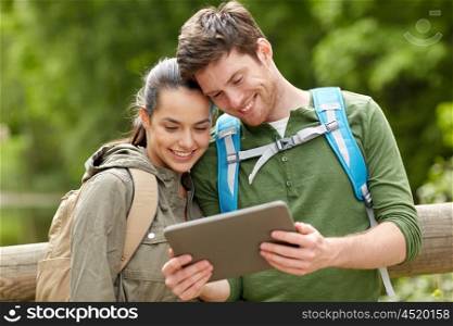 travel, hiking, backpacking, tourism and people concept - smiling couple with backpacks and tablet pc computer in nature