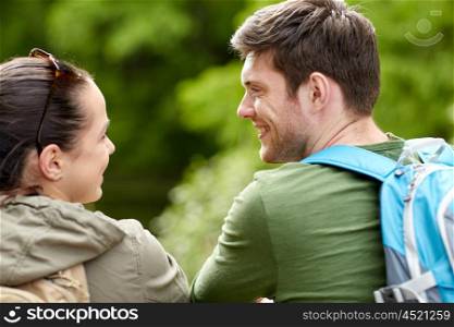 travel, hiking, backpacking, tourism and people concept - smiling couple with backpacks in nature looking and talking to each other