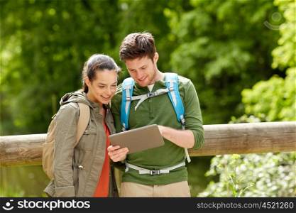 travel, hiking, backpacking, tourism and people concept - smiling couple with backpacks and tablet pc computer in nature