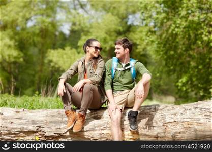 travel, hiking, backpacking, tourism and people concept - smiling couple with backpacks resting and talking in nature