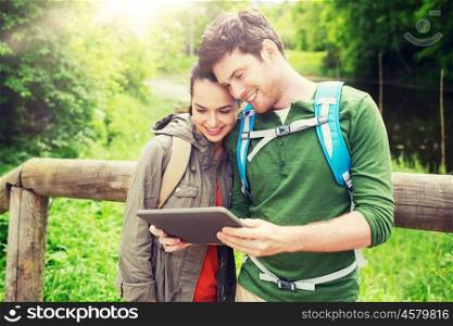 travel, hiking, backpacking, tourism and people concept - smiling couple with backpacks and tablet pc computer in nature. happy couple with backpacks and tablet pc outdoors. happy couple with backpacks and tablet pc outdoors