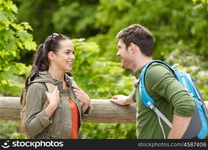 travel, hiking, backpacking, tourism and people concept - smiling couple with backpacks in nature looking and talking to each other