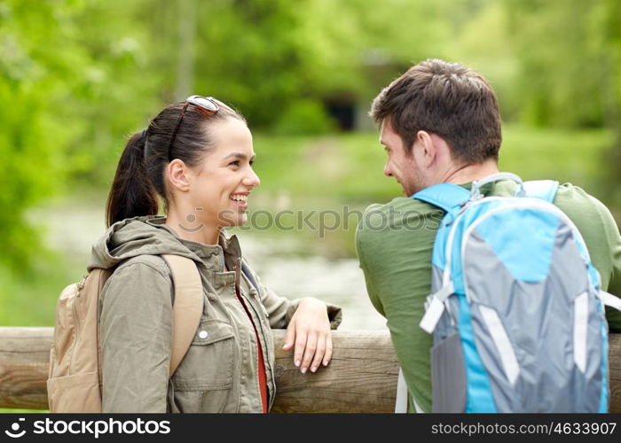 travel, hiking, backpacking, tourism and people concept - smiling couple with backpacks in nature looking and talking to each other