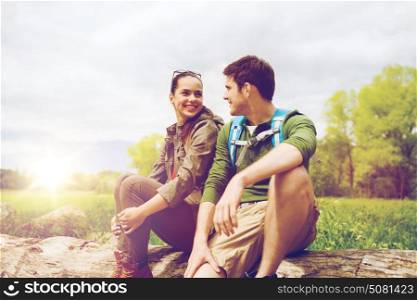 travel, hiking, backpacking, tourism and people concept - smiling couple with backpacks resting and talking in nature. smiling couple with backpacks in nature