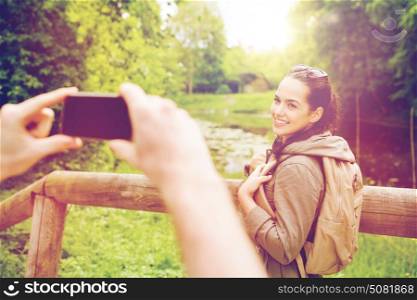 travel, hiking, backpacking, tourism and people concept - smiling couple with backpacks taking picture by smartphone in nature. couple with backpacks taking picture by smartphone