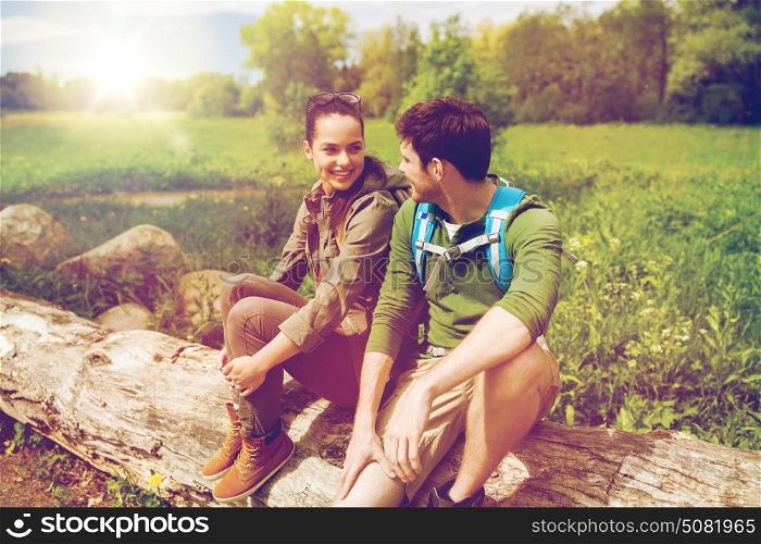 travel, hiking, backpacking, tourism and people concept - smiling couple with backpacks resting and talking in nature. smiling couple with backpacks in nature