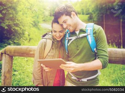 travel, hiking, backpacking, tourism and people concept - smiling couple with backpacks and tablet pc computer in nature. happy couple with backpacks and tablet pc outdoors