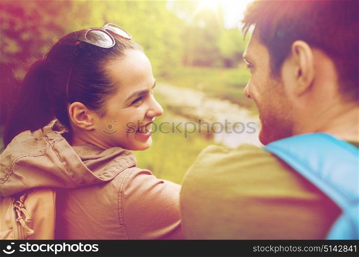 travel, hiking, backpacking, tourism and people concept - smiling couple with backpacks in nature looking at each other. smiling couple with backpacks in nature