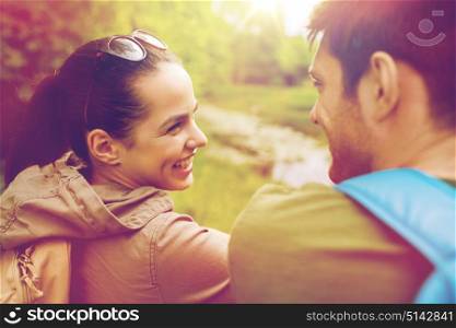travel, hiking, backpacking, tourism and people concept - smiling couple with backpacks in nature looking at each other. smiling couple with backpacks in nature