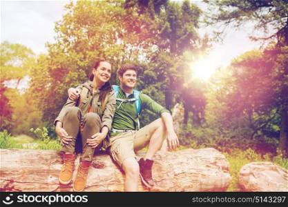 travel, hiking, backpacking, tourism and people concept - smiling couple with backpacks resting and hugging in nature. smiling couple with backpacks in nature