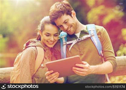 travel, hiking, backpacking, tourism and people concept - smiling couple with backpacks and tablet pc computer in nature. happy couple with backpacks and tablet pc outdoors