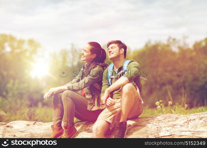 travel, hiking, backpacking, tourism and people concept - smiling couple with backpacks resting and enjoying sun in nature. smiling couple with backpacks in nature