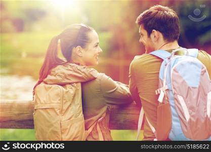 travel, hiking, backpacking, tourism and people concept - smiling couple with backpacks in nature looking and talking to each other. smiling couple with backpacks in nature