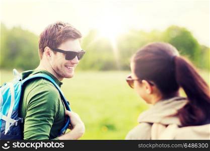 travel, hiking, backpacking, tourism and people concept - smiling couple with backpacks in nature looking at each other. smiling couple with backpacks in nature. smiling couple with backpacks in nature