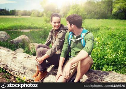 travel, hiking, backpacking, tourism and people concept - smiling couple with backpacks resting and talking in nature. smiling couple with backpacks in nature. smiling couple with backpacks in nature