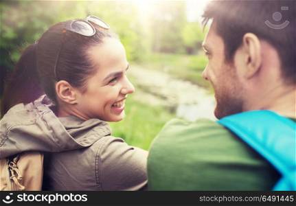travel, hiking, backpacking, tourism and people concept - smiling couple with backpacks in nature looking at each other. smiling couple with backpacks in nature. smiling couple with backpacks in nature