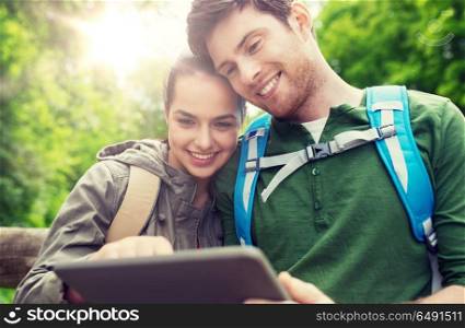 travel, hiking, backpacking, tourism and people concept - smiling couple with backpacks and tablet pc computer in nature. happy couple with backpacks and tablet pc outdoors. happy couple with backpacks and tablet pc outdoors