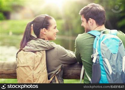 travel, hiking, backpacking, tourism and people concept - smiling couple with backpacks in nature looking and talking to each other. smiling couple with backpacks in nature. smiling couple with backpacks in nature