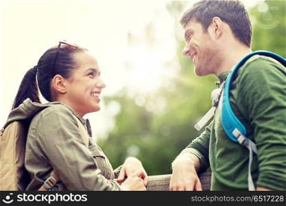 travel, hiking, backpacking, tourism and people concept - smiling couple with backpacks in nature looking and talking to each other. smiling couple with backpacks in nature. smiling couple with backpacks in nature