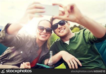travel, hiking, technology, tourism and people concept - smiling couple of travelers taking selfie by smartphone at camping. couple of travelers taking selfie by smartphone. couple of travelers taking selfie by smartphone