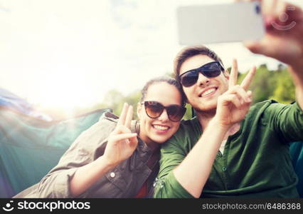 travel, hiking, technology, tourism and people concept - smiling couple of travelers taking selfie by smartphone at camping. couple of travelers taking selfie by smartphone. couple of travelers taking selfie by smartphone