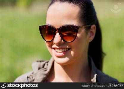 travel, hiking, tourism, eyewear and people concept - face of happy young woman in sunglasses outdoors