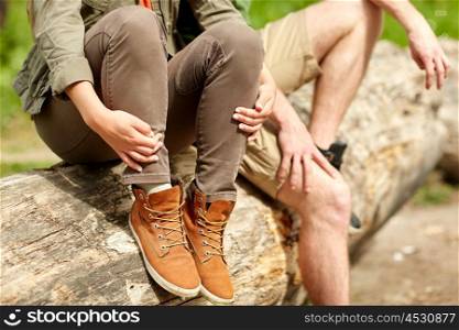 travel, hiking, tourism, footwear and people concept - close up of couple sitting on tree trunk outdoors
