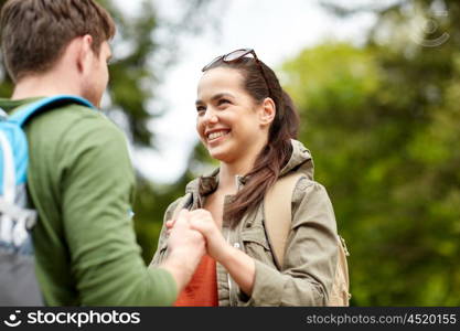 travel, hiking, tourism, love and people concept - happy couple with backpacks holding hands outdoors