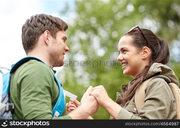 travel, hiking, tourism, love and people concept - happy couple with backpacks holding hands outdoors