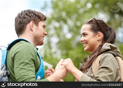 travel, hiking, tourism, love and people concept - happy couple with backpacks holding hands outdoors