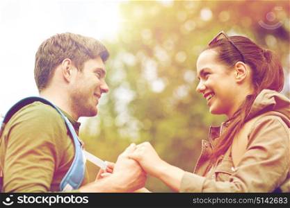 travel, hiking, tourism, love and people concept - happy couple with backpacks holding hands outdoors. happy couple with backpacks hiking outdoors