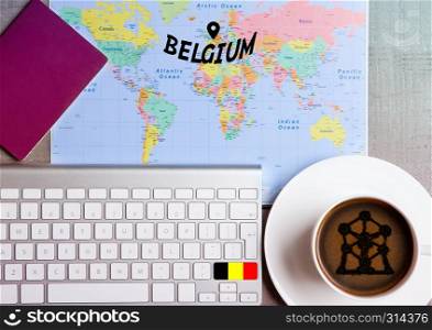 Travel holiday concept with coffee and map with flag on keyboard and passport on wooden table. Travel to Belgium Brussels