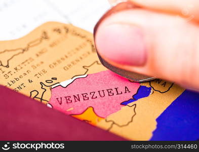 Travel holiday to Venezuela concept with passport and flag with female hand scratching map choosing Venezuela