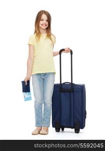 travel, holiday, vacation, childhood and transportation concept - smiling little girl with suitcase, airplane ticket and passport