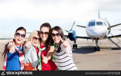 travel, holidays, vacation, happy people concept - smiling teenage girls or young women showing thumbs up at airport