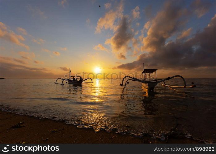 Travel in the morning sunrise in Bali, Indonesia. Traditional fishing boats at Sanur beach, Bali, Indonesia.