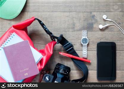 Travel items and accessories with mobile device on wood background, flat lay summer collection