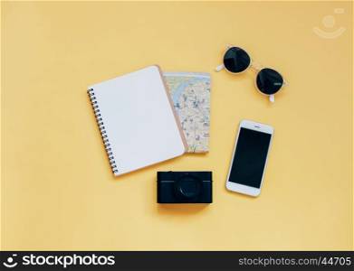 Travel items concept : blank notebook, map, camera, smartphone and sunglasses on yellow background, top view with minimal style
