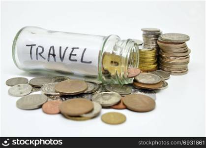 Travel lable in a glass jar with coins spilling out isolated on white background