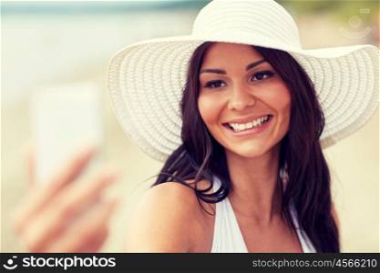 travel, leisure, summer, technology and people concept - sexy young woman taking selfie with smartphone on beach