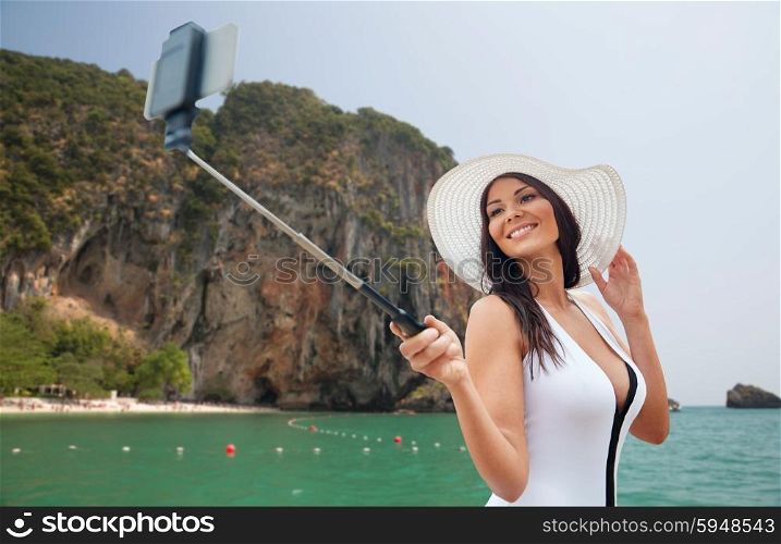travel, leisure, summer, technology and people concept - sexy young woman taking selfie with smartphone over sea and island rock at tropical beach on bali background