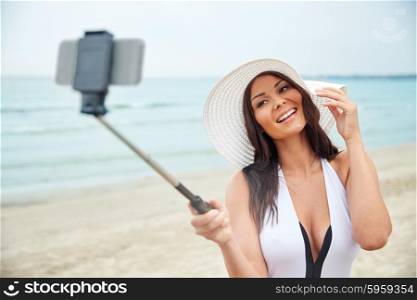 travel, leisure, summer, technology and people concept - sexy young woman taking selfie with smartphone on beach