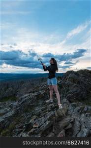 Travel, lesure and freedom concept - woman on the top of Altai mountain, making selfie on beauty summer evening landcape. Travel, lesure and freedom concept