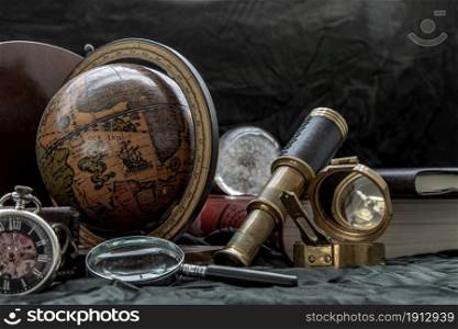 Travel or adventure concept background. Pocket watch, binoculars, antique compass, globe, magnifying glass and stack of books on dark background. Journey Concept, Vintage Style.