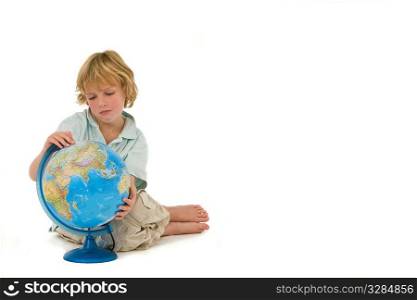 Travel or Enivironmental concept studio shot of a young blond boy looking at a globe